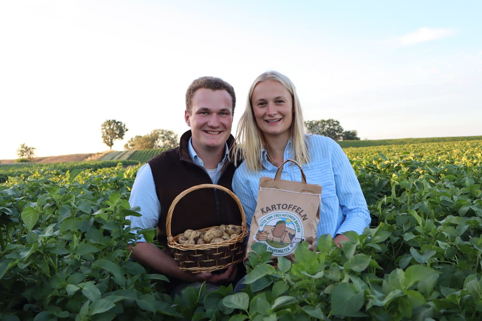 Hof Grapengeter: Paar mit frisch geernteten Kartoffeln und einer Tüte Kartoffeln auf dem Feld in Neuratjensdorf