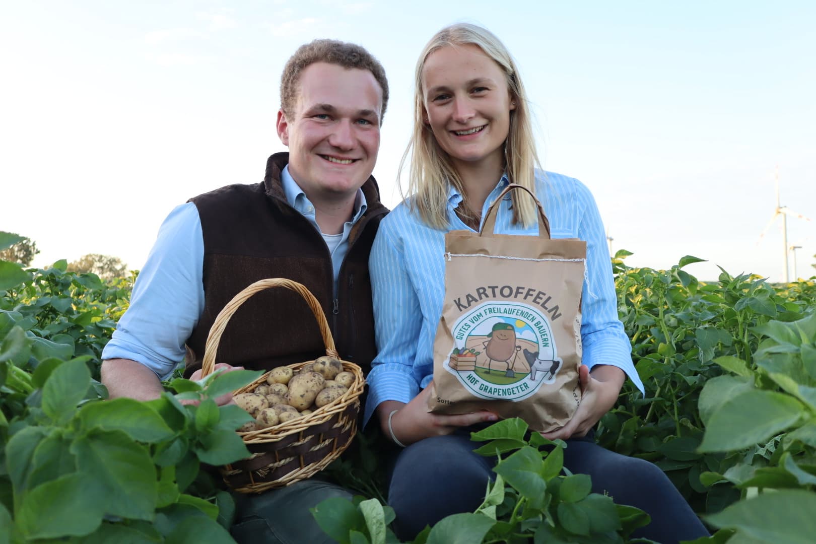 Hof Grapengeter: Paar mit frisch geernteten Kartoffeln und einer Tüte Kartoffeln auf dem Feld in Neuratjensdorf